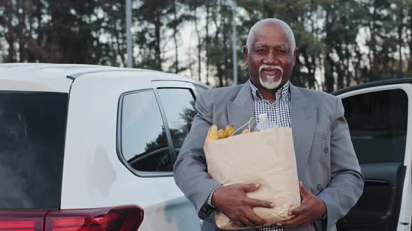Handsome Old African American Man Smiling Holding Food in Hands Bought in Fruit Shop Happy Carefree alt