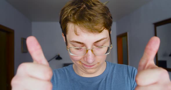 Selfconfident Teenager Looking at the Camera Nods Approvingly and Shows Thumbs Up alt