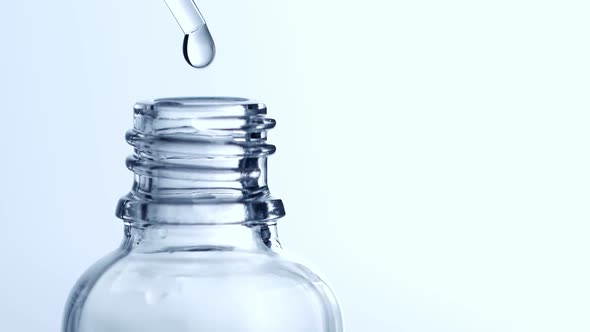 Drop of Liquid Falling From Glass Lab Pipette in Transparent Bottle Isolated on White Background alt