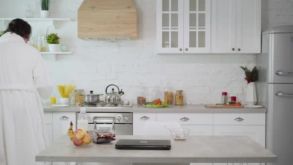 Confident Young Man Walking with Healthful Apple Leaving Kitchen alt