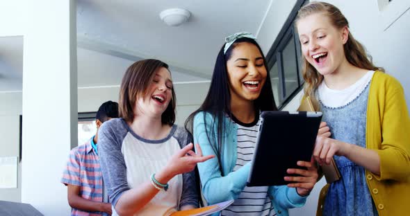 Group of school friends using digital tablet in corridor alt