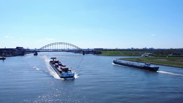 Shipping Inland Vessels Cruising At Noord River With Arch Bridge In The Distance At Hendrik-Ido-Amba alt