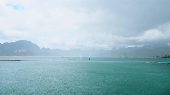 Heavy Rain Dropping on Turquoise Lake with Mountains on Background on Summer Day alt