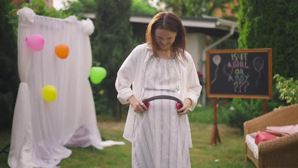 Smiling Pregnant Woman Holding Headphones on Belly Dancing in Slow Motion on Backyard alt