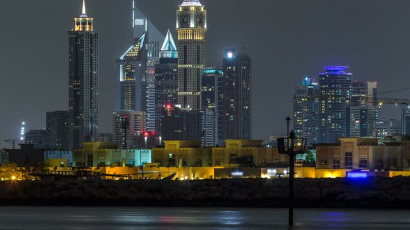Modern Dubai City Skyline Timelapse at Night with Illuminated Skyscrapers Over Water Surface alt
