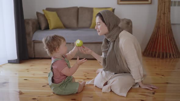 Little Boy Eating Green Apple Chewing and Sitting on Knees alt