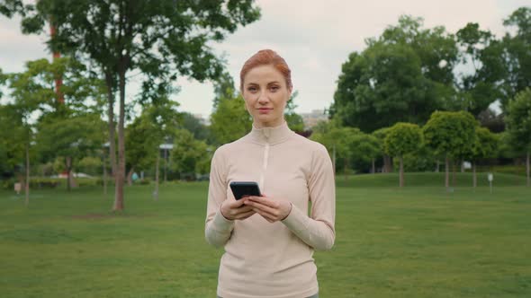 Female taking break from jogging and using smartphone alt