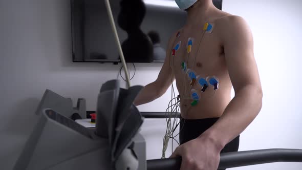 Unrecognizable man walking on treadmill during cardiac stress test alt