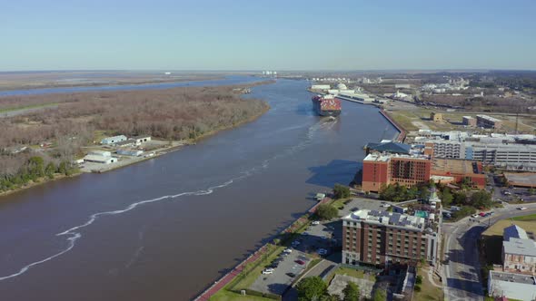 Ferry heads down Savannah River trailed by tugboat alt