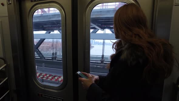 Commuter on subway train in New York looking at smart phone