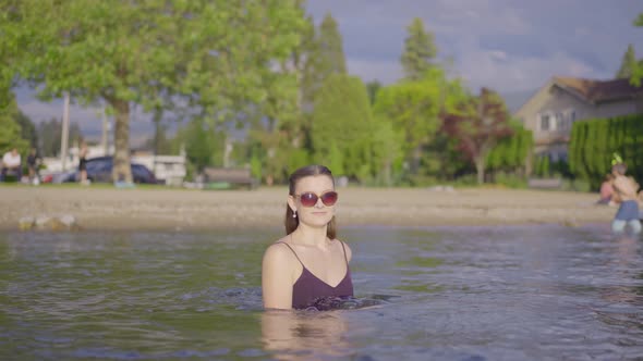 Young attractive girl in sunglasses playing in the water alt