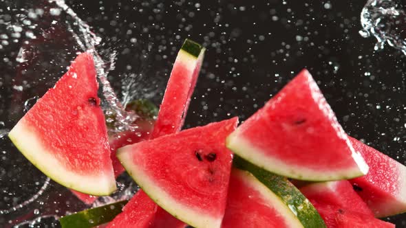 Super Slow Motion Shot of Flying Fresh Melon Cuts and Water Side Splash on Black at 1000 Fps alt
