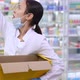 Overworking Ill Asian Woman Putting Pills on Shelves in Drugstore Coughing - VideoHive Item for Sale
