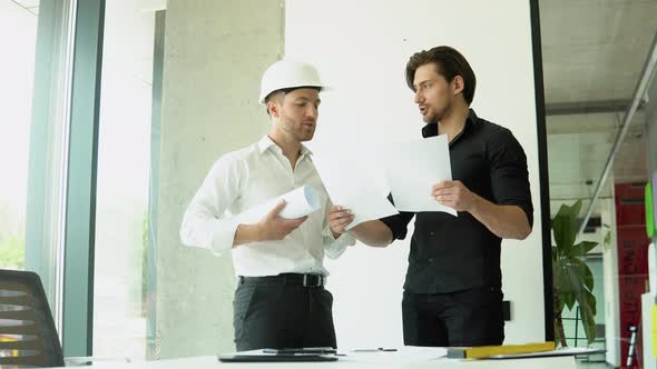 Engineer and Architect Reviewing Office Blueprints and Technical Drawings alt