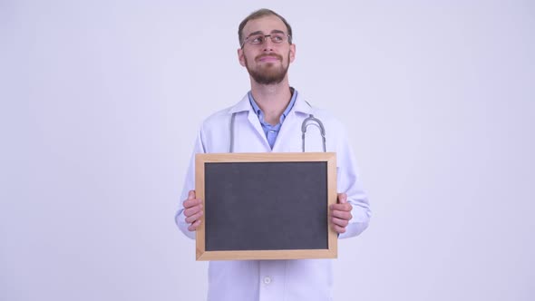 Happy Bearded Man Doctor Thinking While Holding Blackboard