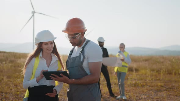 International Team of Business Partners Standing Together Among Wind Turbines alt