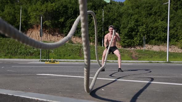 Muscular Man Doing Waves with Undulation Ropes.