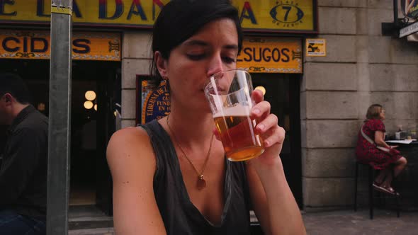 Beautiful Caucasian woman drinks beer in a bar in Madrid (Spain). Spanish girl sitting on a terrace alt