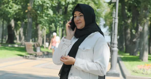 Cheerful Arab Woman Talking By Mobile Phone on Summer Street Gesturing alt