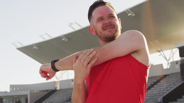 Caucasian male athlete stretching before running on sunny day alt