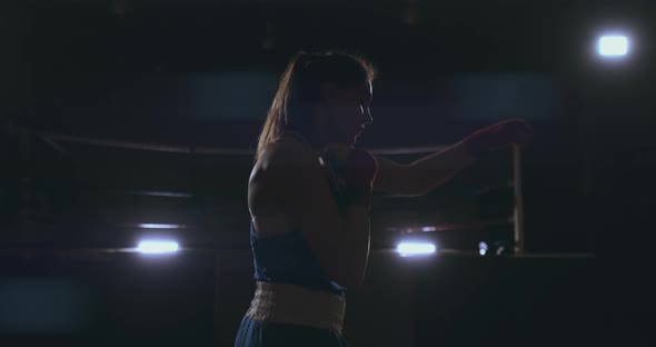 Professional Female Boxer Blows Conducting a Fight with a Shadow in a Dark alt