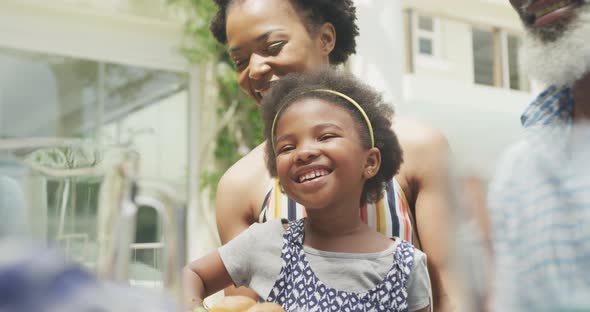 Happy african american family talking and having breakfast in garden alt