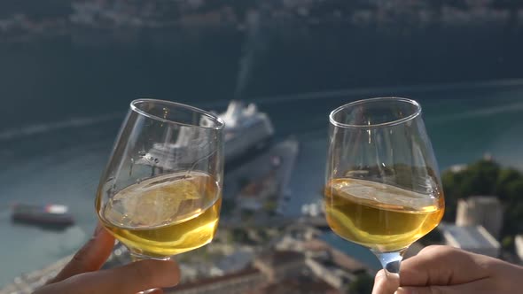 Two Glasses of White Wine Touch Each Other on the Background of the Bay