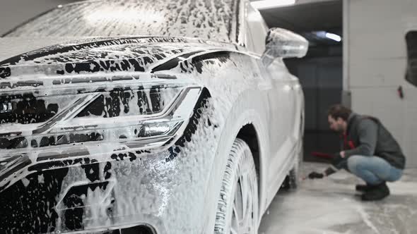 Car Service The Worker Washes Car Rims with a Soft Brush with Shampoo alt
