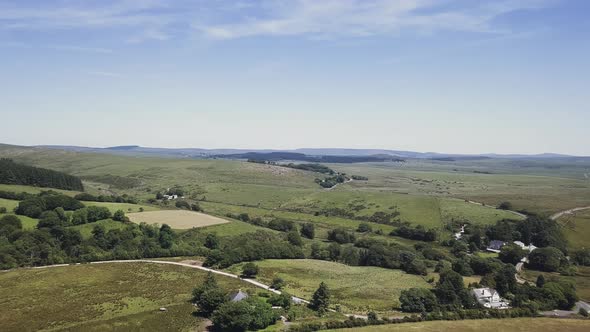 Aerial,ing forward slowly over green farmland in Dartmoor, UK, high altitude alt