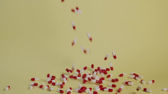 Slow motion wide shot of a handful of pills as they fall vertically and bounce around. alt