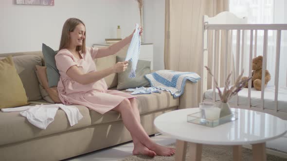 Expectant Woman Preparing Newborn Boy Clothes alt