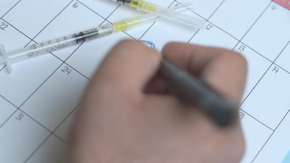 A Person Writing on Calendar Reminder  Vaccine Day alt