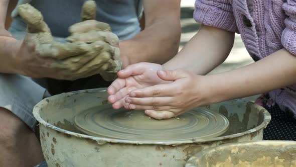 Master teaches girl to make pottery from clay. Rotating Potters wheel. close up