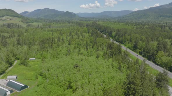 Aerial of Bellingham, Washington pushing alongside highway and towards mountains and foothills. alt