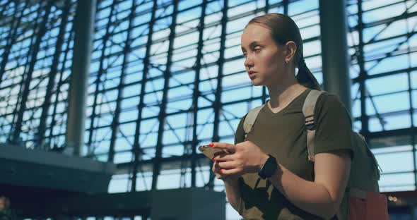 A Woman Looks at the Screen of a Mobile Phone To Find Your E-ticket on the Plane alt