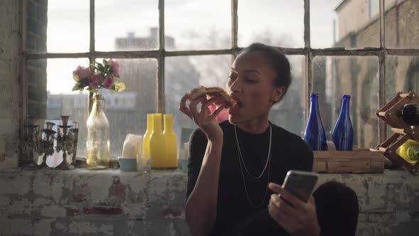 Young adult woman eating Pizza at home with mobile phone