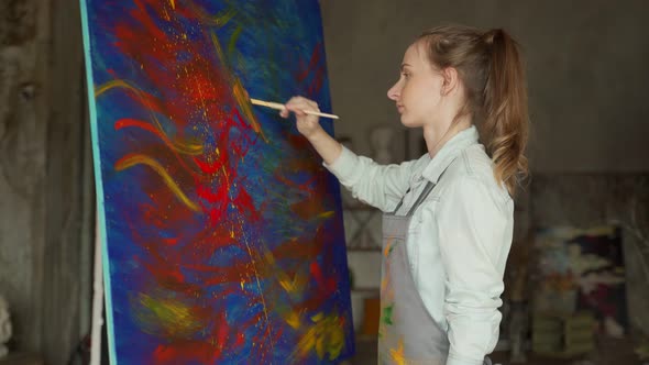 Female Artist in Front of an Easel Painting with a Brush Using Oil or Acrylic Paint alt
