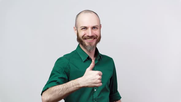 Happy bearded man showing thumbs up sign over white background. Good job.