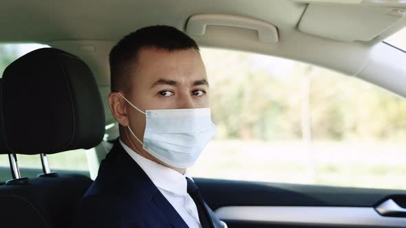 Businessman Wearing Medical Mask in Prevention for Coronavirus and Driving His Car to Work