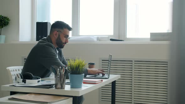 Mad Office Worker Using Laptop Hitting Table with Fists and Going Away From Workplace alt