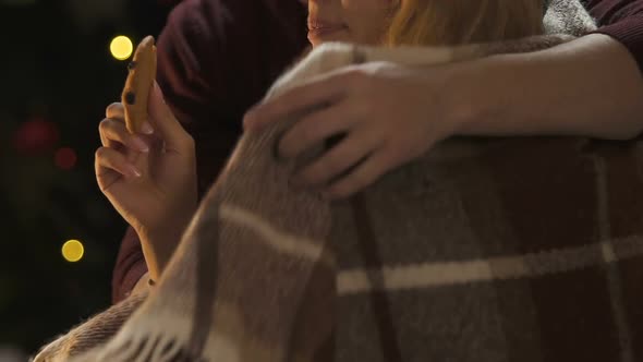Woman Eating Cookie, Husband Wrapping Her With Blanket, Care for Beloved Closeup alt