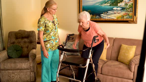 Closeup of home healthcare nurse helps elderly woman get up from couch and use a walker. alt