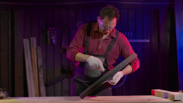 Worker in Overalls Is Repairing the Rear Wheel of a Bicycle in a Garage. alt