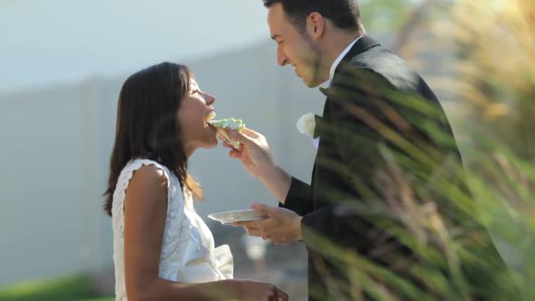 Bride and groom at wedding feed each other cake alt