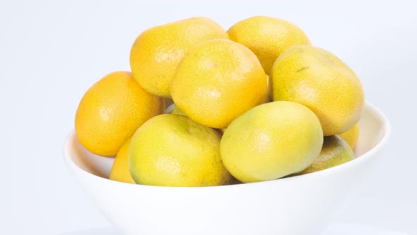 Fresh tangerines on white plate rotating in front of camera against the white background alt