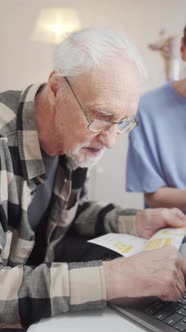 Young Woman Helps Elderly Father Pay Bills Online alt