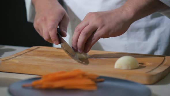 chef on cutting board cuts onions into slices for vegetable salad with knife