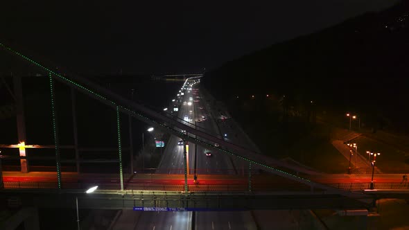 People Walk Along the Pedestrian Parkovy Bridge at Night Aerial View alt
