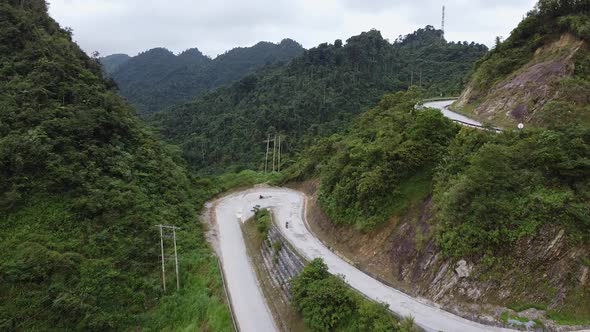 Aerial View of A Crooked Road in the Mountains Around A Green Forest