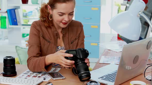 Female executive talking on mobile phone while looking photo on digital camera 4k alt